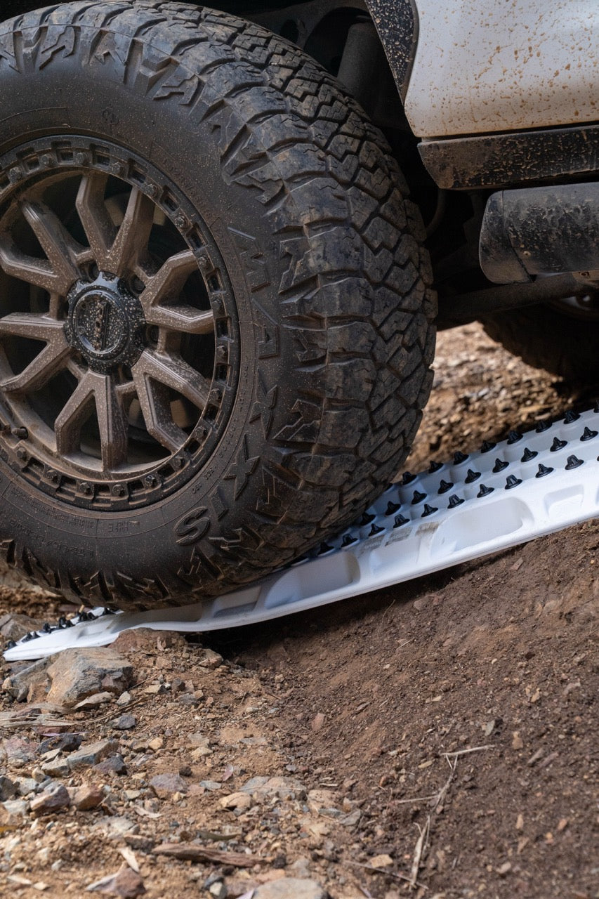 Close-up of a vehicle tire with a mud flap on a dirt road